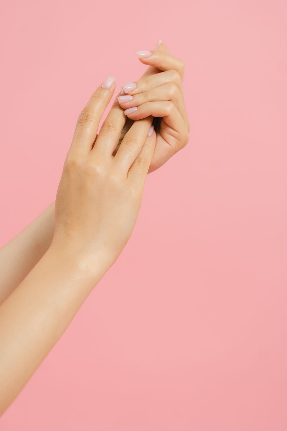Manicured hands against a soft pink background